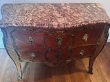 a marble top chest of drawers on a wooden floor