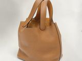 un sac à main en cuir beige à deux anses sur fond blanc