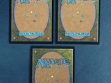 three magic the gathering cards are sitting on a blue surface