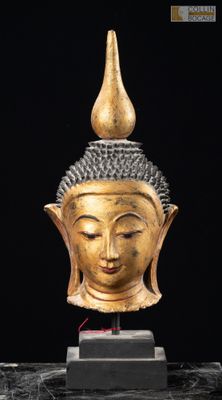 une image représentant une tête de Bouddha en or posée sur un socle en marbre