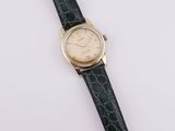 a gold plated wrist watch with a black alligator skin strap