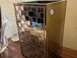 une poubelle argentée posée sur une table à côté d'un miroir