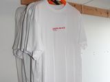 un t-shirt blanc suspendu à un cintre en bois dans une pièce