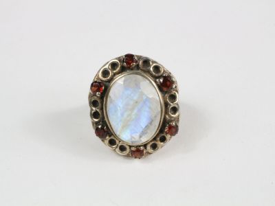 un gros plan d'une bague ornée d'une pierre blanche entourée de grenats