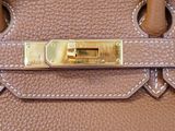 the handle of a brown purse with a gold lock on it