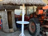 a thatched umbrella in the middle of a barn with a tractor in the background