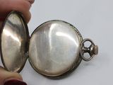 a person holding a silver pocket watch in their hand