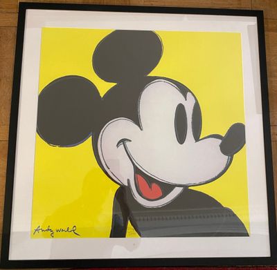 framed mickey mouse art print in a black frame on a wooden floor