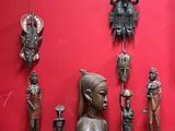 de nombreuses statues en bois exposées dans une pièce rouge