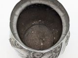 a metal cup with a handle on a white surface