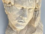 marble bust of a young man with a wreath of flowers on his head