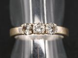 gros plan d'une bague en or ornée de trois diamants