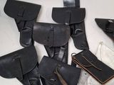 five pairs of black leather holsters on a white table