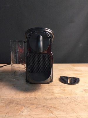 une cafetière noire posée sur une table à côté d'un verre d'eau