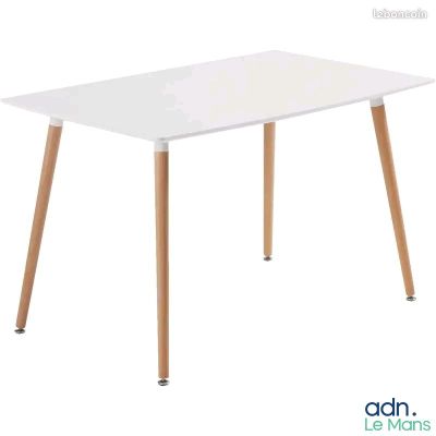 La table est blanche, avec des pieds en bois et un plateau blanc.