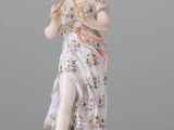 statue of a woman holding a bird on a rock on a white surface