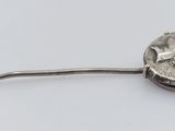 a silver object with a flower on it on a white surface