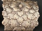 boîte plaquée argent, ornée de fleurs et de feuilles sur un fond noir