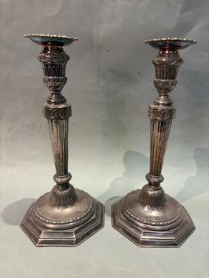 pair of antique silver candlesticks on display in a glass case