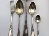 five silver spoons and two silver spoons on a white surface