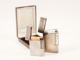 two silver lighters sitting on top of each other on a white surface