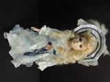 a doll with blonde hair and blue dress on a black surface