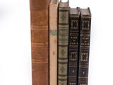 several old books are stacked on top of each other on a white surface