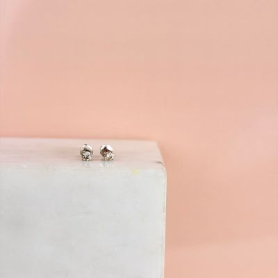 deux boucles d'oreilles en diamant posées sur un bloc de marbre blanc