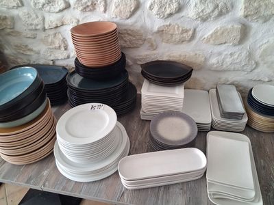 a lot of plates and bowls on a table with a stone wall in the background