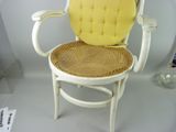 a white chair with a yellow cushion and a wicker seat