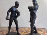 une paire de figurines en bronze représentant un homme et une femme, posées sur une table en marbre