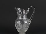 a clear glass pitcher with a handle on a black background