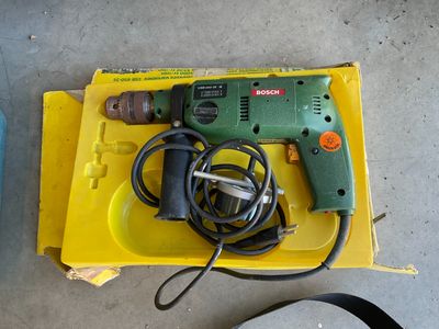 une perceuse filaire posée sur une boîte jaune