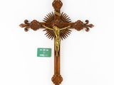 an antique wooden crucifix with a sunburst and a green tag
