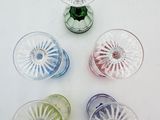 four different colored glass vases on a white surface