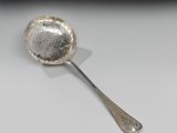 une cuillère en argent posée sur une surface blanche, sur fond noir