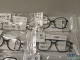 several pairs of glasses are wrapped in plastic bags on a table