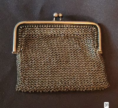 a small metal purse with a chain handle on a black surface
