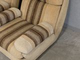 pair of beige upholstered chairs with striped cushions in a room