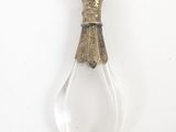 une image représentant une bouteille en verre munie d'une poignée métallique, posée sur une surface blanche
