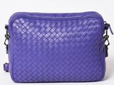a purple bag sitting on top of a white table next to a white wall