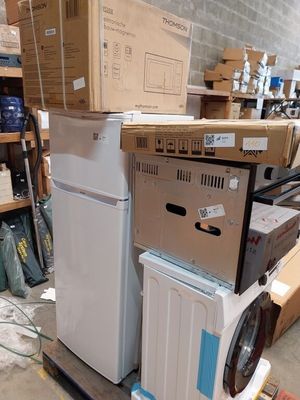 a stack of appliances and a washing machine in a warehouse