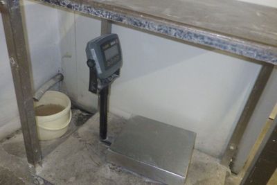 une photo d'une salle de bains avec un pèse-personne numérique posé par terre