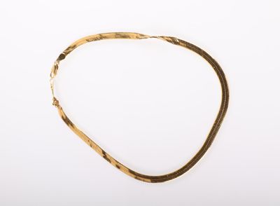 gros plan d'un collier en or sur une surface blanche