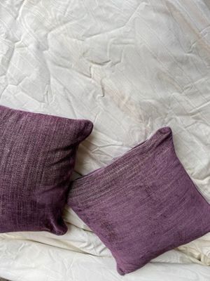 deux oreillers violets sur un lit blanc recouvert d'une couette blanche