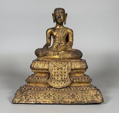 une statue en or représentant un Bouddha assis sur une pile de livres