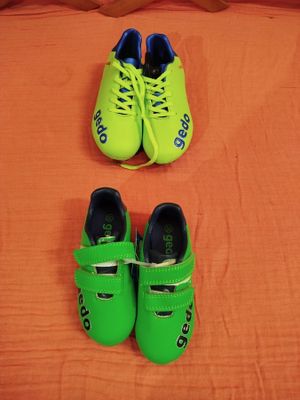 deux paires de chaussures vertes posées sur un lit aux draps orange