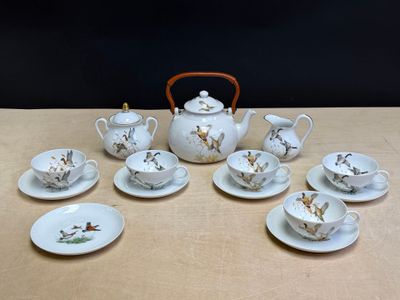 une table sur laquelle sont posés une théière, des tasses et des soucoupes