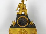 a gold clock with a statue on top of it