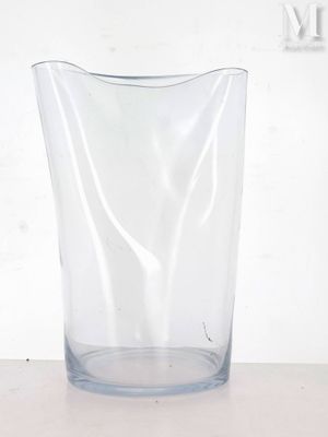 a clear glass vase sitting on a table with a white wall in the background